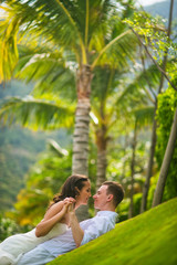 the bride and groom playing on the green grass against the palm trees in the summer