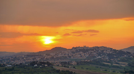 colorful warm sunset with little town Osimo on the green hills in Marche , Italy