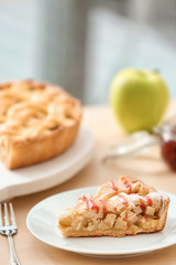 Plate with piece of tasty homemade apple pie on table