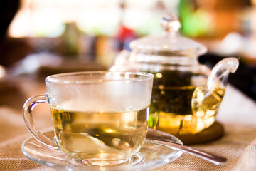Beverages, good morning and breakfast concept - Cup of white green tea and teapot on the table
