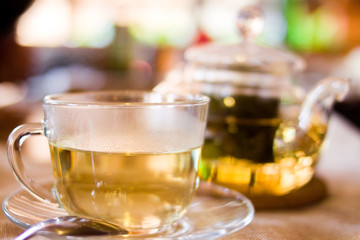 Beverages, good morning and breakfast concept - Cup of white green tea and teapot on the table