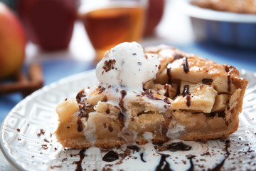 Piece of tasty homemade apple pie with ice cream on plate, closeup