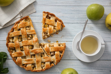 Tasty homemade apple pie and cup of tea on wooden table