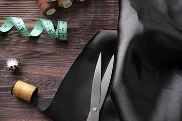 Fabric and sewing accessories on wooden background