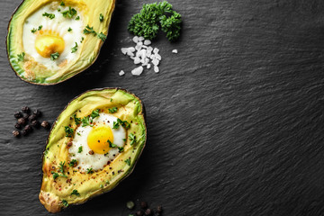 Baked avocado with eggs on dark textured background