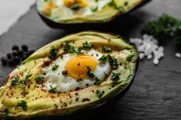 Baked avocado with egg on dark textured background, closeup