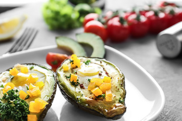 Baked avocado with eggs on plate, closeup