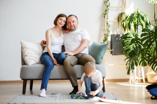 Photo of young parents with son sitting on sofa