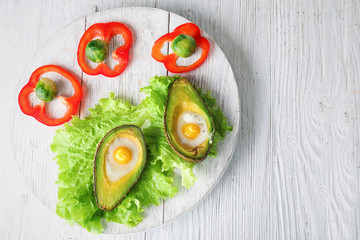Baked avocados with eggs and vegetables on wooden table