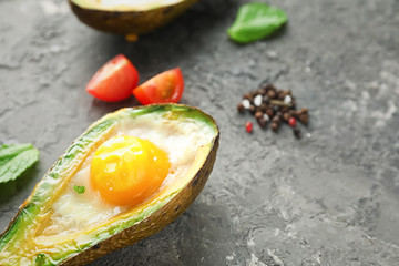 Baked avocado with egg on grey textured background