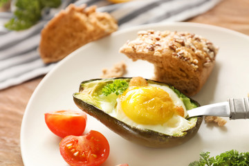 Baked avocado with eggs and vegetables on table, closeup