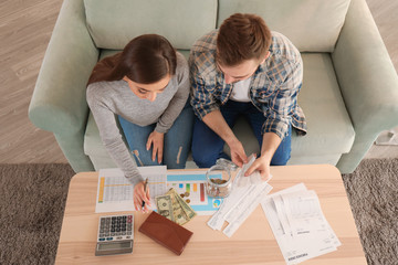 Couple with pay bills, calculator and money counting expenses indoors. Money savings concept