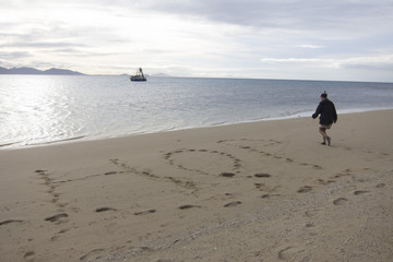 woman writing Hope into the sandy beach of Hope Island, inside Great Barrier Reef, Queensland Australia