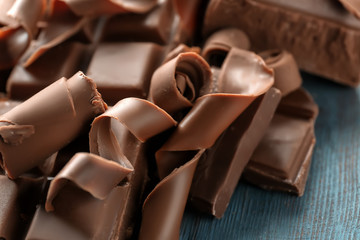 Delicious chocolate curls with pieces on table, closeup