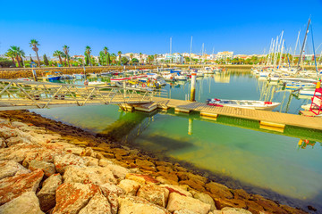 Fototapeta premium Beautiful landscape of yacht, charter and motorboats in Marina de Lagos. The Marina is located in Bay of Lagos, Algarve coast, Portugal, Europe. Summer holidays. Blue sky.
