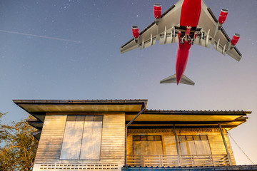Big passenger plane over wooden house in countryside