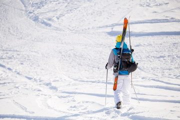 Photo from back of sports woman with skis and sticks in winter