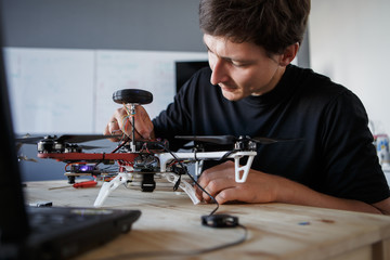 Photo of young man cleaning quadrocopter at table