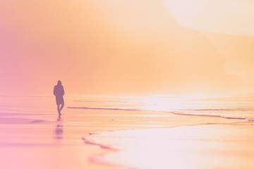 lonely person walking on beach at sunset