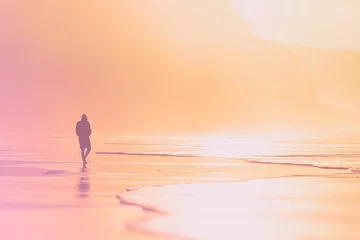 Tableaux ronds sur aluminium brossé Plage et mer lonely person walking on beach at sunset