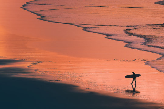 distant surfer silhouette in the shore at sunset