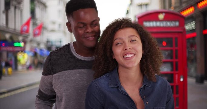 POV of African American couple video chatting from London, View from computer screen of black male and female standing on London street smiling and waving, 4k