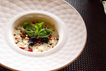 good morning, breakfast and healthy food concept - Tasty oatmeal with strawberries, mint leaves, blueberries and chocolate in white bowl