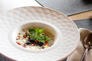 good morning, breakfast and healthy food concept - Tasty oatmeal with strawberries, mint leaves, blueberries and chocolate in white bowl