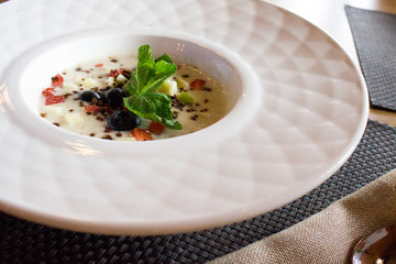 good morning, breakfast and healthy food concept - Tasty oatmeal with strawberries, mint leaves, blueberries and chocolate in white bowl