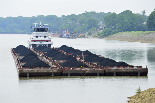 Photo of a riverboat pushing tons of coal in barges on the river
