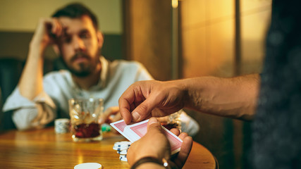 Side view photo of friends sitting at wooden table. Friends having fun while playing board game.