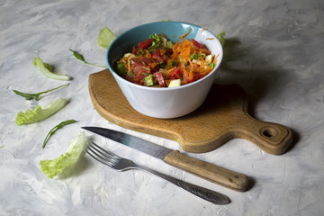 The bowl of organic salad and cutlery on a table.