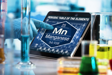 researcher consulting on the digital tablet data of the chemical element Manganese Mn