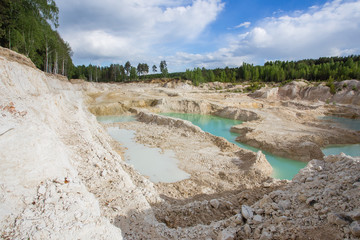 Open pit quarry ore white kaoline mining with blue sky and water