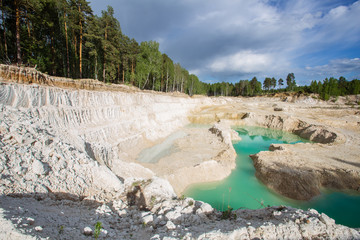Open pit quarry ore white kaoline mining with blue sky and water