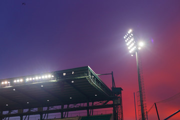 Roof of football stadium between competition under twilight sky at night time.