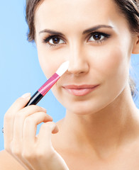 Woman with cosmetics brush, on blue