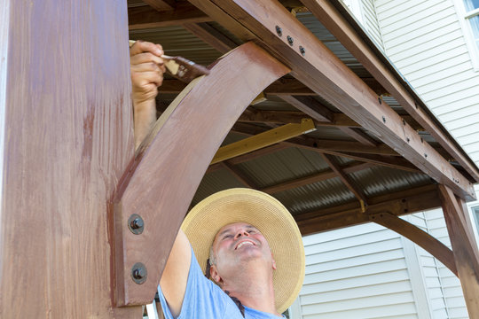 Middle-aged man staining woodwork on a gazebo