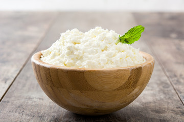 Fresh cottage cheese in a wooden bowl on wooden table