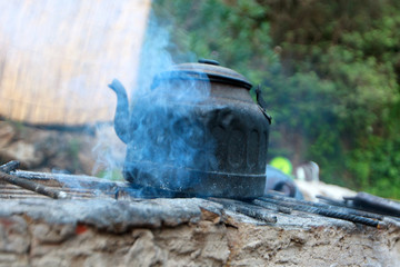 An old water kettle on the fireplace in the camp