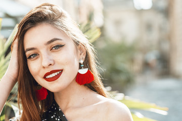 Outdoor close up portrait of yong beautiful happy smiling woman with red lips, long hair, wearing...