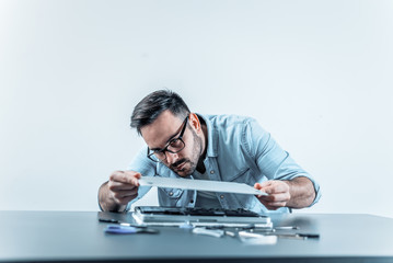 Handsome engineer assembling repaired laptop computer.