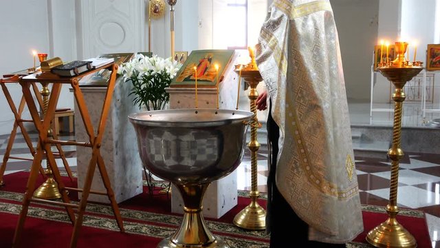the priest lights the burning candle with water in the font for the ritual of baptism.