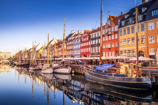 COPENHAGEN, DENMARK - MAY 6, 2018: picturesque view of historical buildings and moored boats reflected in calm water, copenhagen, denmark