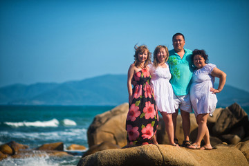 Fototapeta na wymiar A group of four friends standing on a rock, posing under a blue sky