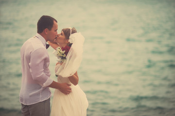 The bride and groom kissing in the background of the sea