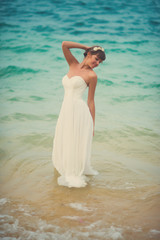 Fototapeta na wymiar Bride in wedding dress posing in sea water