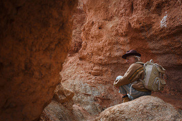 Beautiful young girl in hare, hat and with backpack travels among sands in wild