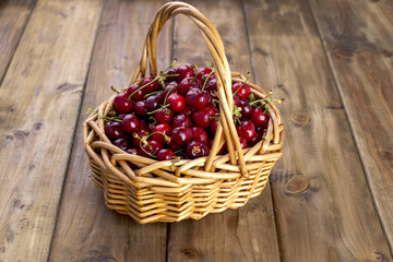 A large basket of ripe cherries. Delicious and sweet berries. Wooden background, free space for text. Retro style.