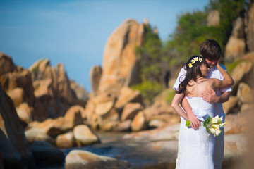 the bride and groom hugging gently against the beautiful scenery, mountains and sea